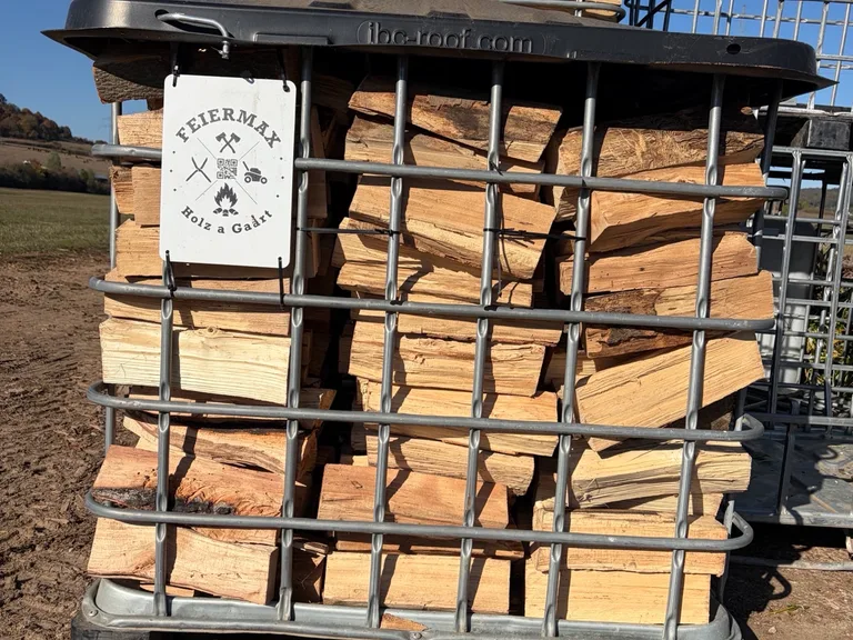 Caisse grillagée remplie de bois de chauffage empilé, avec la plaque FEIERMAX