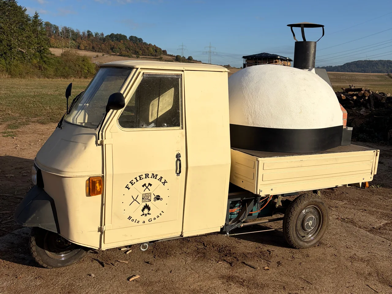 Der mobile FEIERMAX-Pizzaofen auf seinem Ape 50, mit dem Logo auf der Tür